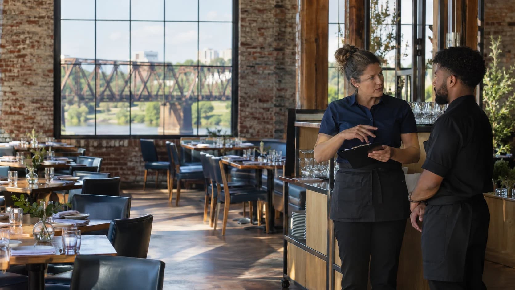 A supervisor briefing a server in a Virginia brick restaurant overlooking the James River.